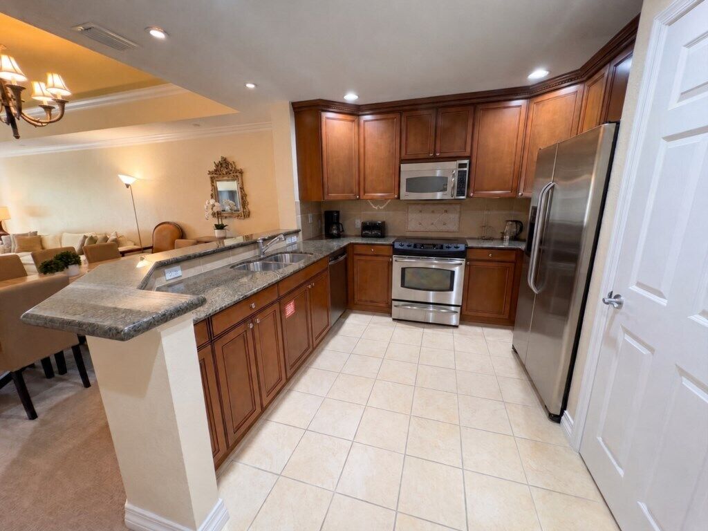 A modern kitchen with wooden cabinets, stainless steel appliances, and a marble countertop.