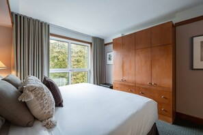 A hotel room with a large bed, a wardrobe, and a window with curtains. - Blackcomb Ski-in/out | Complex pool & hot tub (Whistler)