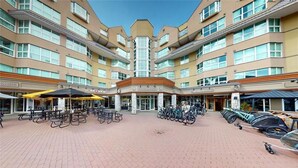 A hotel courtyard with multiple floors, outdoor seating, and bicycles. - Blackcomb Ski-in/out | Complex pool & hot tub (Whistler)