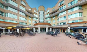 A hotel courtyard with multiple floors, outdoor seating, and bicycles. - Blackcomb Ski-in/out | Complex pool & hot tub (Whistler)