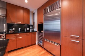 Eine moderne Küche mit Holzschränken, Edelstahlgeräten und einer schwarzen Arbeitsplatte.