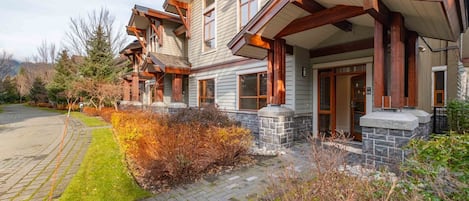 A two-story house with a stone foundation, large windows, and a covered porch.