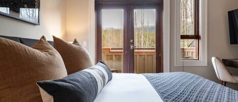 Ein Hotelzimmer mit Bett, Kissen, Schreibtisch und Blick ins Freie.