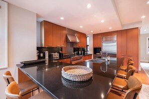 A modern kitchen with a central island, stainless steel appliances, and wooden cabinetry. - Private Hot Tub | Central AC | BBQ | Garage (Whistler)