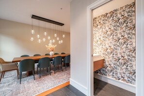 A modern dining area with a wooden table, dark chairs, and hanging pendant lights. - Private Hot Tub | Central AC | BBQ | Garage (Whistler)