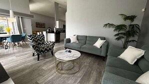 Una sala de estar moderna con un sofá gris, una mesa de centro redonda y un sillón estampado.