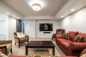 A modern living room with a flat-screen TV, two sofas, a coffee table, and a patterned rug. - Luxury | Private garage | Private hot tub | BBQ (Whistler)