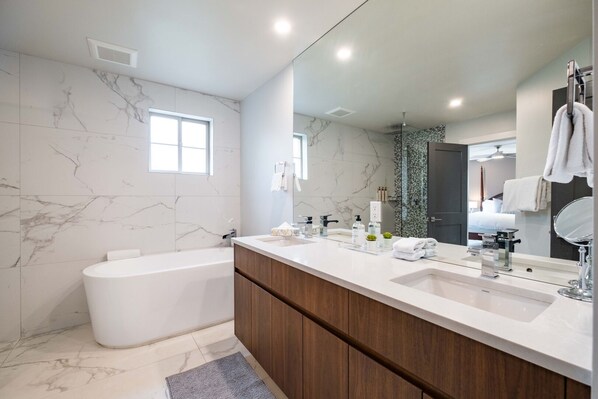 Une salle de bain moderne avec une baignoire sur pieds, un grand meuble-lavabo avec un miroir et des murs en marbre.