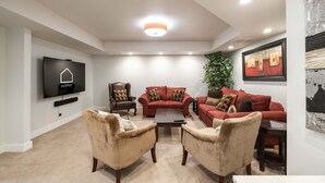 A modern living room with a flat-screen TV, a fireplace, and a large window. - Luxury | Private garage | Private hot tub | BBQ (Whistler)