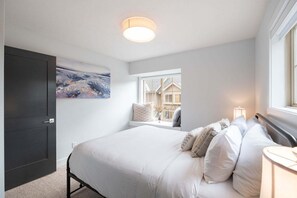 Un dormitorio con cama, ventana con vistas, puerta y una lámpara en el techo.