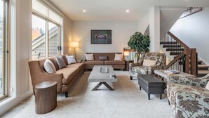A spacious living room with a sofa set, a coffee table, and a patterned armchair. - Luxury | Private garage | Private hot tub | BBQ (Whistler)
