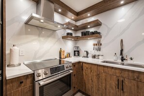 A modern kitchen with a built-in oven, stainless steel range, and a coffee maker. - Great location | Complex hot tub | BBQ | Pets (Whistler)