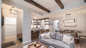 A modern living room with a sectional sofa, a dining area with a wooden table, and a kitchen with pendant lighting. - Great location | Complex hot tub | BBQ | Pets (Whistler)