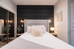 A modern bedroom with a large bed, bedside tables, and a mirror. - Great location | Complex hot tub | BBQ | Pets (Whistler)