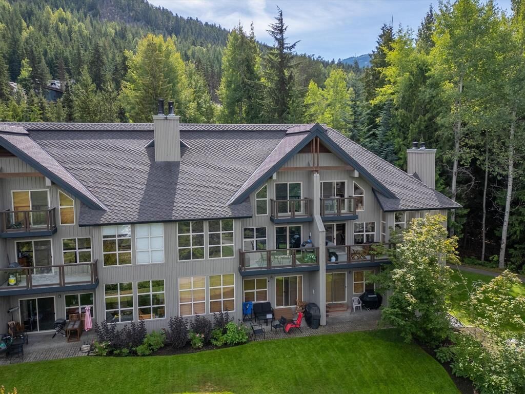 A multi-story building with a balcony, large windows, and a well-maintained lawn.