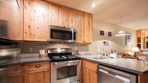 Una cocina con gabinetes de madera, electrodomésticos de acero inoxidable, encimera de granito y lavavajillas.