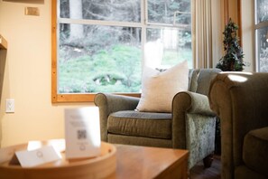 A cozy room with a large window, a chair, a small table, and a plant. - Close to Blackcomb | Shared hot tub | Free parking (Whistler)