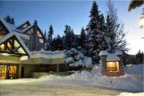 A snow-covered lodge with a stone entrance and a lit sign reading "Willamwood." - Close to Blackcomb | Shared hot tub | Free parking (Whistler)