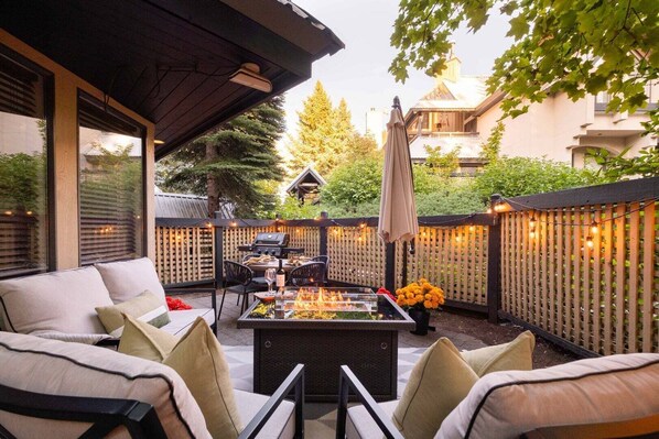 An outdoor patio with a fire pit, seating, and a grill. - Benchlands Townhome | Golf, Ski & Free Parking (Whistler)