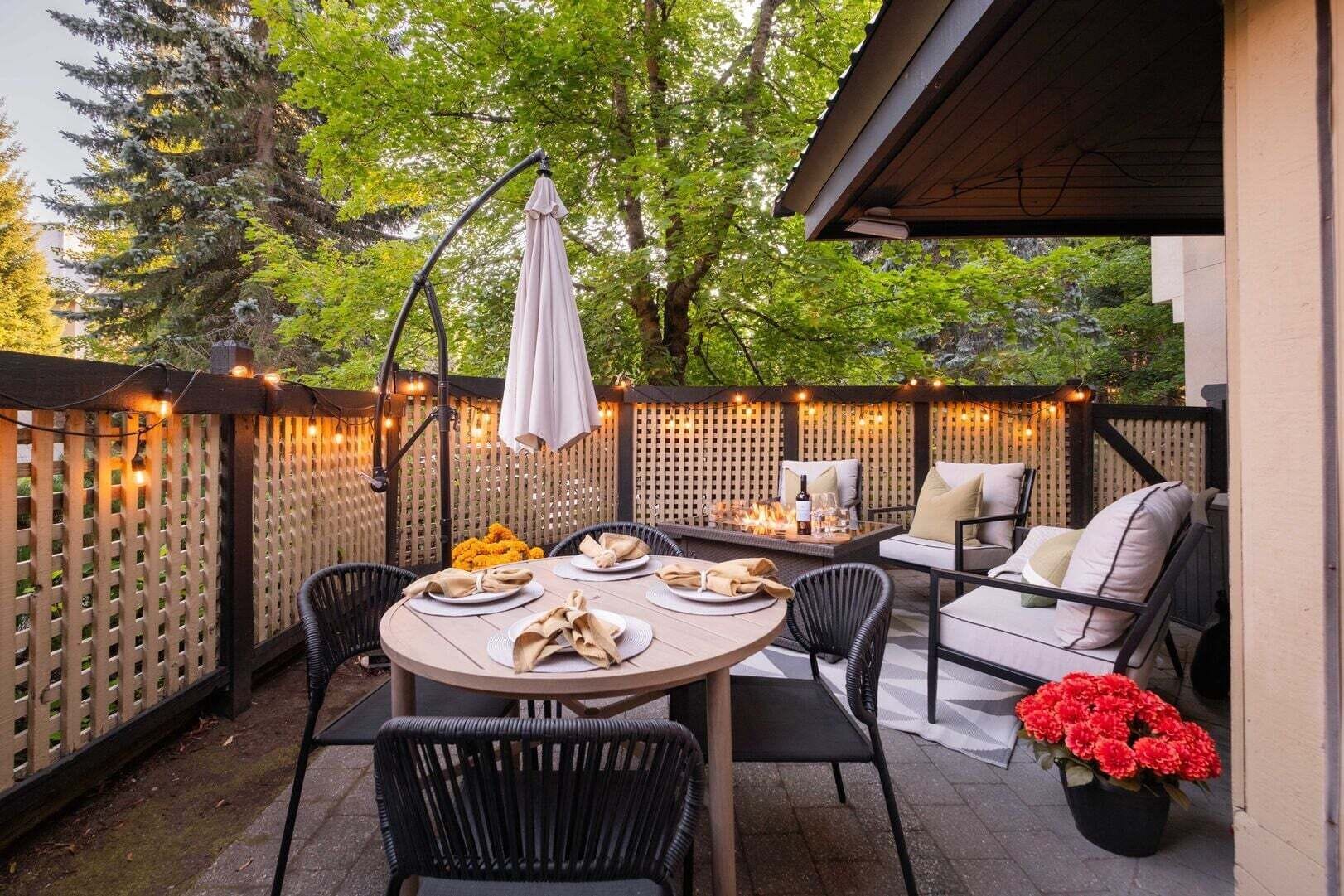 An outdoor patio with a round table, chairs, a sofa, and a fire table.