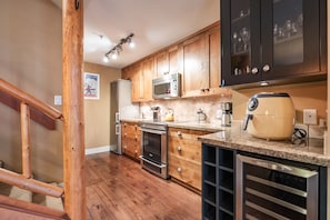 A modern kitchen with wooden cabinets, stainless steel appliances, and a built-in wine cooler. - Foxglove Townhome Near Skiing & Golf (Whistler)