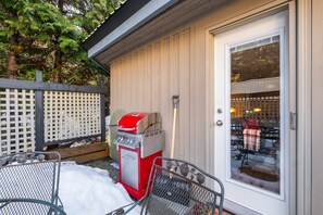 A patio with a red grill, a metal table, and a glass door leading to an indoor area. - Foxglove Townhome Near Skiing & Golf (Whistler)