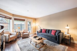 Ein Wohnzimmer mit einem dunkelblauen Sofa, beigefarbenen Sesseln, einem Holztisch und einem gemusterten Teppich.