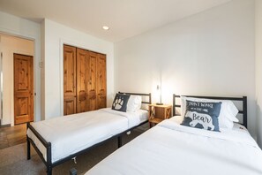 Ein Hotelzimmer mit zwei Einzelbetten, Holzschränken, einem Nachttisch mit Lampe und einer Wandleuchte.