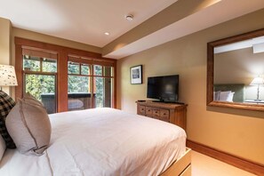 Ein Schlafzimmer mit einem großen Bett, einem Fernseher auf einer hölzernen Kommode und einem großen Spiegel an der Wand.