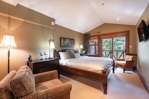 Ein Schlafzimmer mit einem großen Bett, einem Nachttisch, einem Sessel, einem Fenster mit Ausblick und einem Deckenventilator.