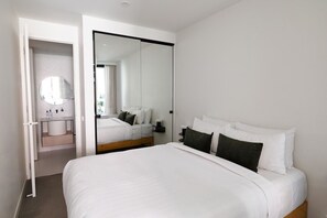 Un dormitorio con una cama grande, un espejo y un baño con lavamanos y espejo.