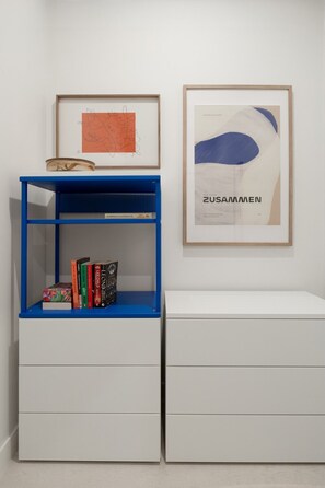 A room with a blue bookshelf, a white dresser, and two framed artworks on the wall. - Stylish Collingwood Apartment with Balcony (Collingwood)