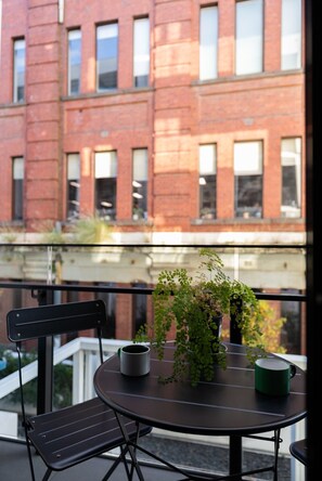 A balcony with a table, chairs, and a potted plant. - Stylish Collingwood Apartment with Balcony (Collingwood)
