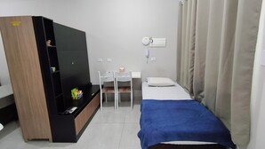 A compact hotel room with a bed, a desk, a chair, a wardrobe, and a bedside table. - Standard apartment 103 (Paranavaí)