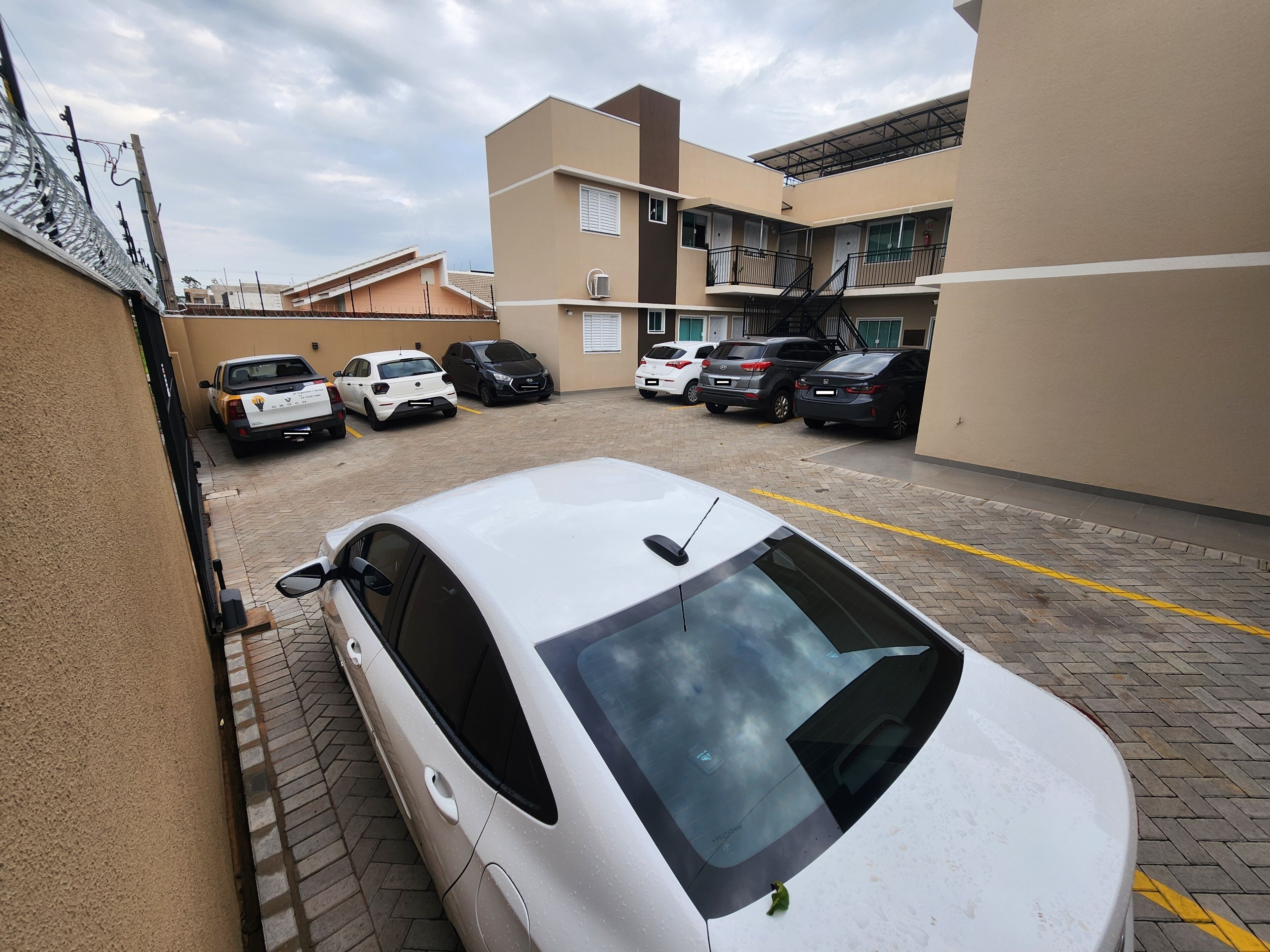 Un parcheggio con diverse auto, un edificio su più piani e cielo sereno.
