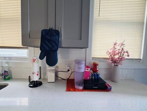 A kitchen with a kettle, coffee maker, and a coffee machine on the counter. - Renovated 3BR | Bay Windows | EWR 15 Min (East Orange)