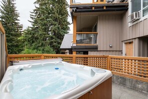 A hot tub on a wooden deck with a view of a building and trees in the background. - Townhome with Private Hot Tub & Pool (Whistler)