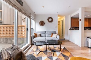 Un salon moderne avec un canapé, deux tables basses et un tapis à motifs.