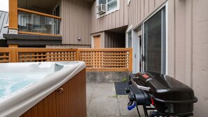 A hot tub, a barbecue grill, and a wooden fence in a residential setting. - NEW Townhome | Private hot tub | Complex pool (Whistler)