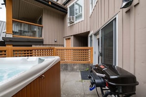 A hot tub, a barbecue grill, and a wooden fence in a residential setting. - NEW Townhome | Private hot tub | Complex pool (Whistler)