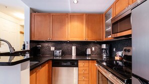 A modern kitchen with wooden cabinets, a dishwasher, a stove, and a microwave. - NEW Townhome | Private hot tub | Complex pool (Whistler)
