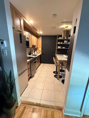 Eine moderne Küche mit Holzschränken, einem eingebauten Backofen und einem Essbereich mit Tisch und Stühlen.