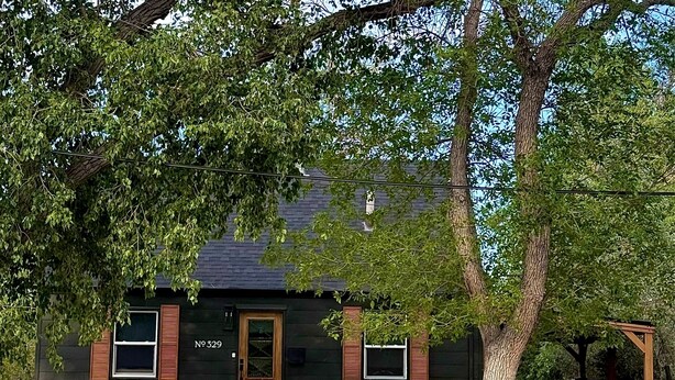 A house with a dark exterior, a wooden door, and shutters. - Central R&R Cape Cod (Casper)