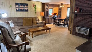 Ein gemütliches Wohnzimmer mit Sofa, Sessel, Couchtisch und Essbereich mit Stühlen.