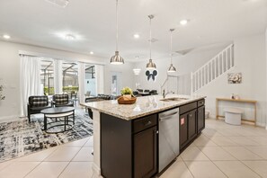 A modern kitchen with a central island, dark cabinetry, and pendant lighting. - 5 BD/ 4.5 BA/ Windsor Cay (1252 BI) (Clermont)