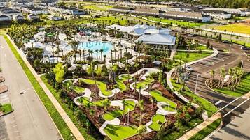An aerial view of a resort with a swimming pool, landscaped areas, and a parking lot.