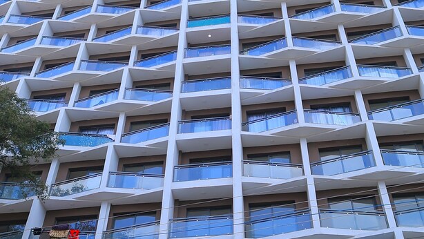 Un grattacielo con numerosi balconi e un cartello con la scritta 'Balozi Suites by Bexmex Homes'.