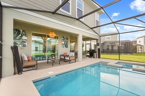 Ein Swimmingpool mit überdachter Terrasse, Gartenmöbeln und Blick auf eine Wohngegend.