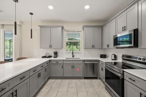 A modern kitchen with grey cabinets, a stainless steel dishwasher, a built-in oven, and a microwave. - Resort Amenities Included! 7 BD/ 6 BA/ Storey Lake 4585 TB (Kissimmee)