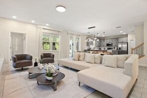 A modern living room with a sectional sofa, two armchairs, a coffee table, and a kitchen in the background. - Resort Amenities Included! 7 BD/ 6 BA/ Storey Lake 4585 TB (Kissimmee)